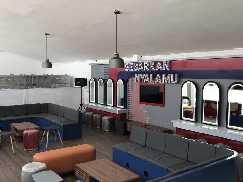 Area lounge asrama dengan signage neon dan furniture custom
